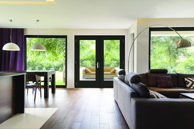 Classically elegant living room with sofa, a metal standing lamp open to the dining room, glass doors going to backyard with black trim